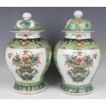 A pair of Chinese famille verte porcelain jars and covers, late Qing dynasty, each baluster body