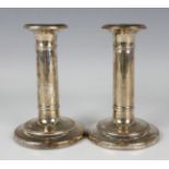 A pair of Edwardian silver candlesticks, each with a circular stepped sconce above a cylindrical