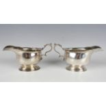 A pair of George V silver sauceboats, each with shaped rim and scroll handle, on a stepped oval