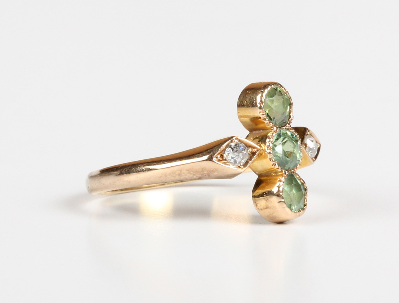 A gold, demantoid garnet and diamond ring, early 20th century, collet set with three circular cut