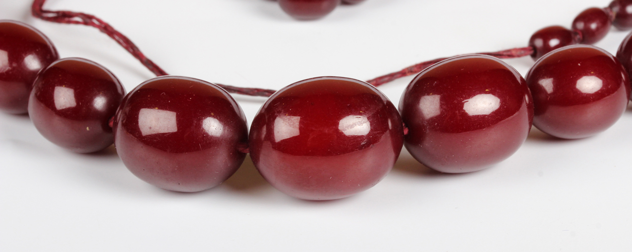 A single row necklace of graduated oval cherry coloured imitation amber beads, early 20th century, - Image 5 of 5