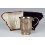 A George V silver christening tankard with flared rim and engraved inscription above a basal foliate