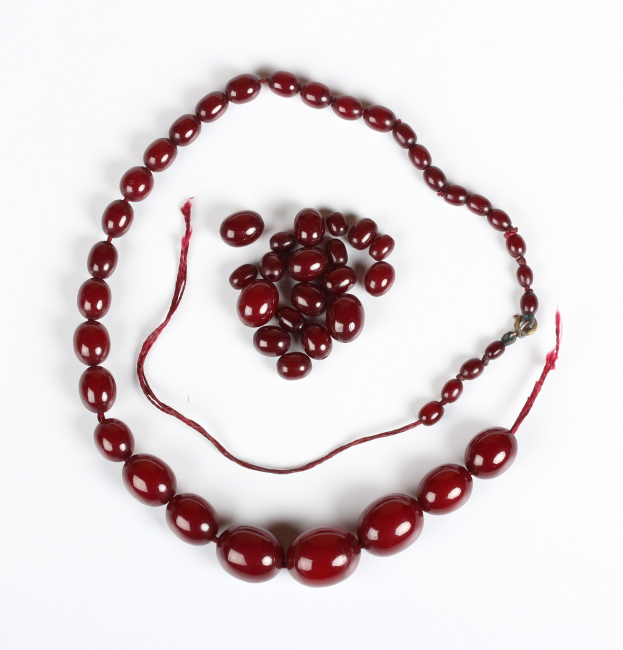 A single row necklace of graduated oval cherry coloured imitation amber beads, early 20th century,