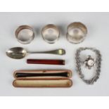 A small group of silver, comprising three napkin rings, teaspoon, Victorian brooch in the form of