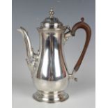 A George VI silver hot water pot of tapered low-bellied form with domed hinged lid and foliate