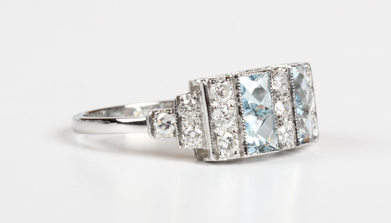 A platinum, aquamarine and diamond ring, mounted with four square cut aquamarines alternating with