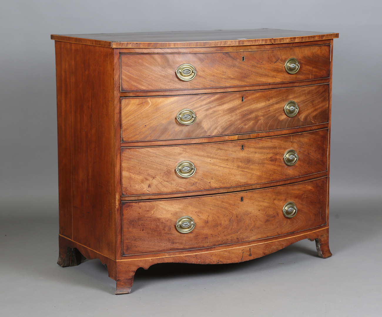 A George III mahogany bowfront chest of oak-lined drawers, the top with a wide crossbanded border,