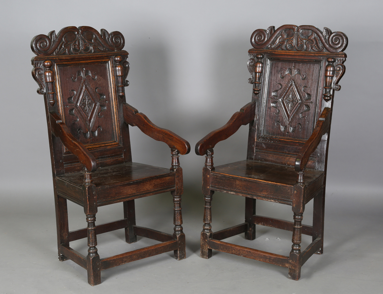 A pair of 17th century provincial oak Wainscot armchairs with carved panel backs and solid panel
