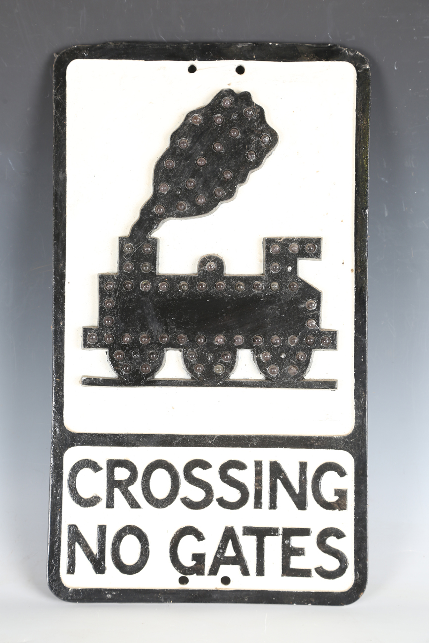A cast alloy railway 'Crossing No Gates' sign, the outline of the locomotive inset with