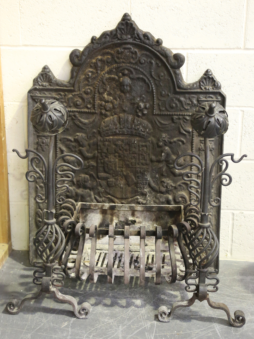 An early 20th century wrought iron fire basket and a pair of matching dogs with rosette finials,