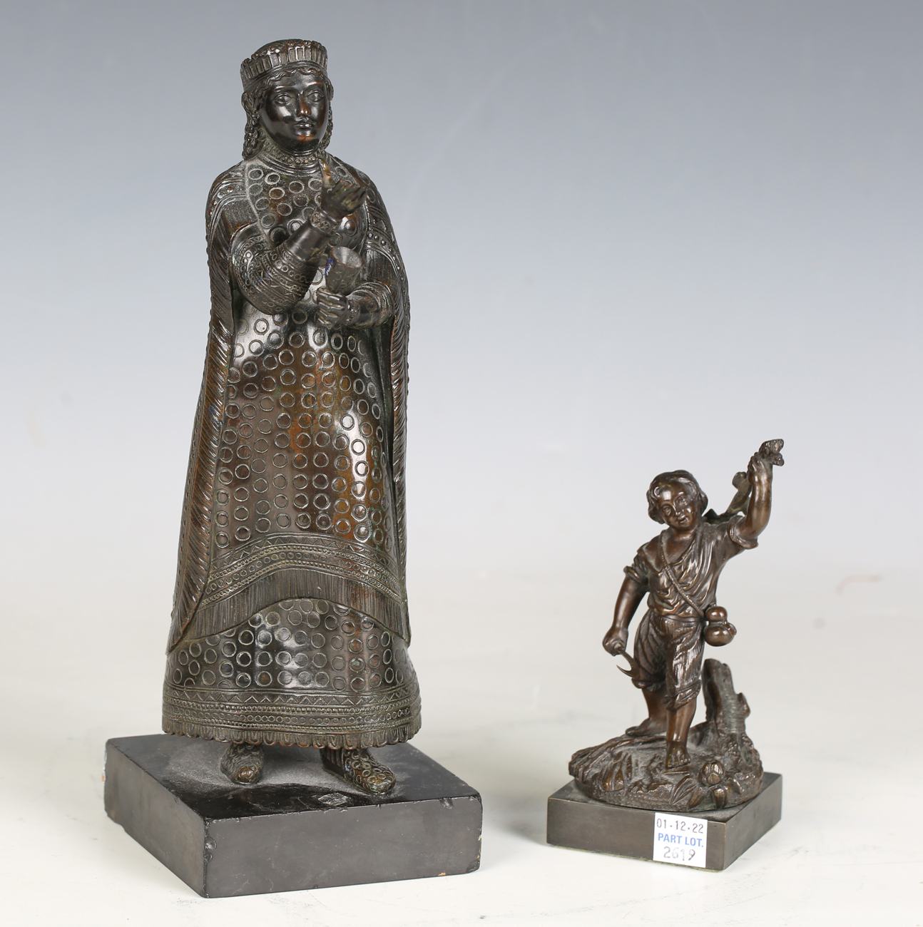 A 19th century Continental patinated bronze figure of a regal female holding a goblet and dish,