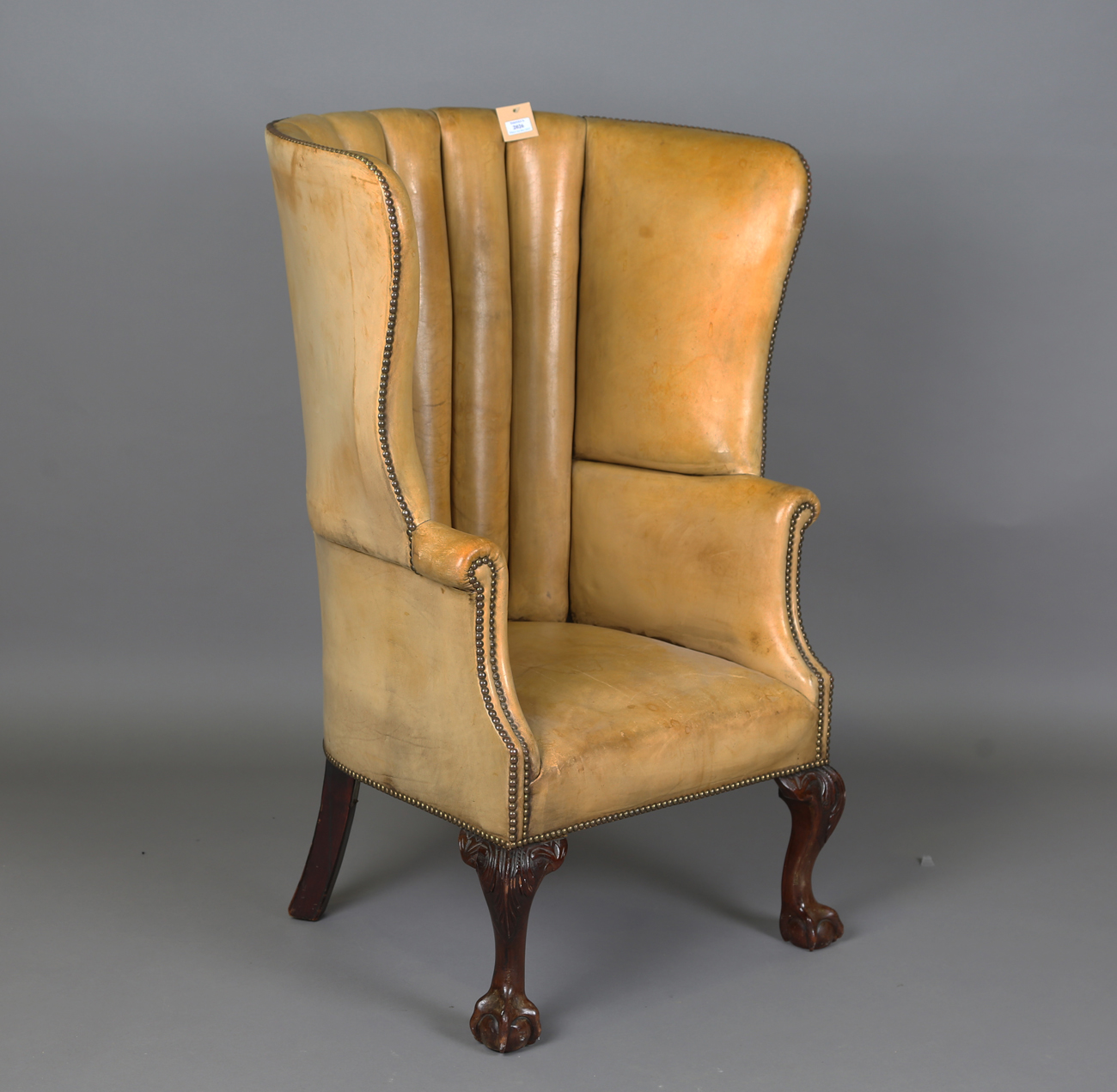 A 20th century George III style armchair, upholstered in studded tan leather, raised on carved