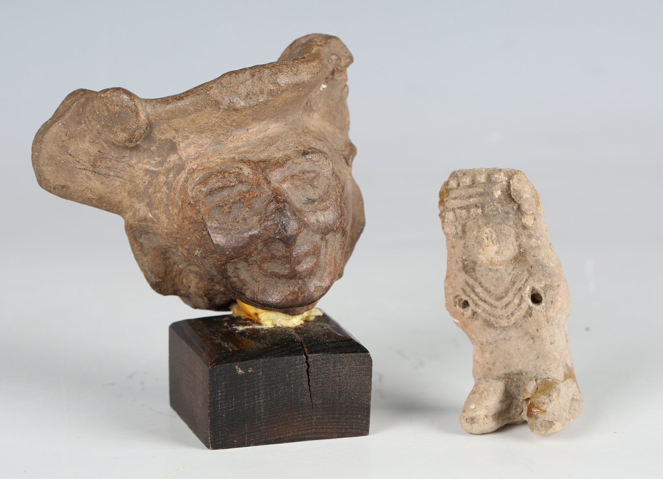A pre-Columbian pottery mask, width 7.5cm, mounted on a wooden base, together with a pre-Columbian