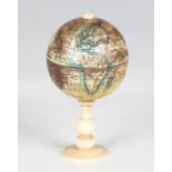 An early 20th century printed tin miniature globe, raised on a turned bone stand, overall height 7.