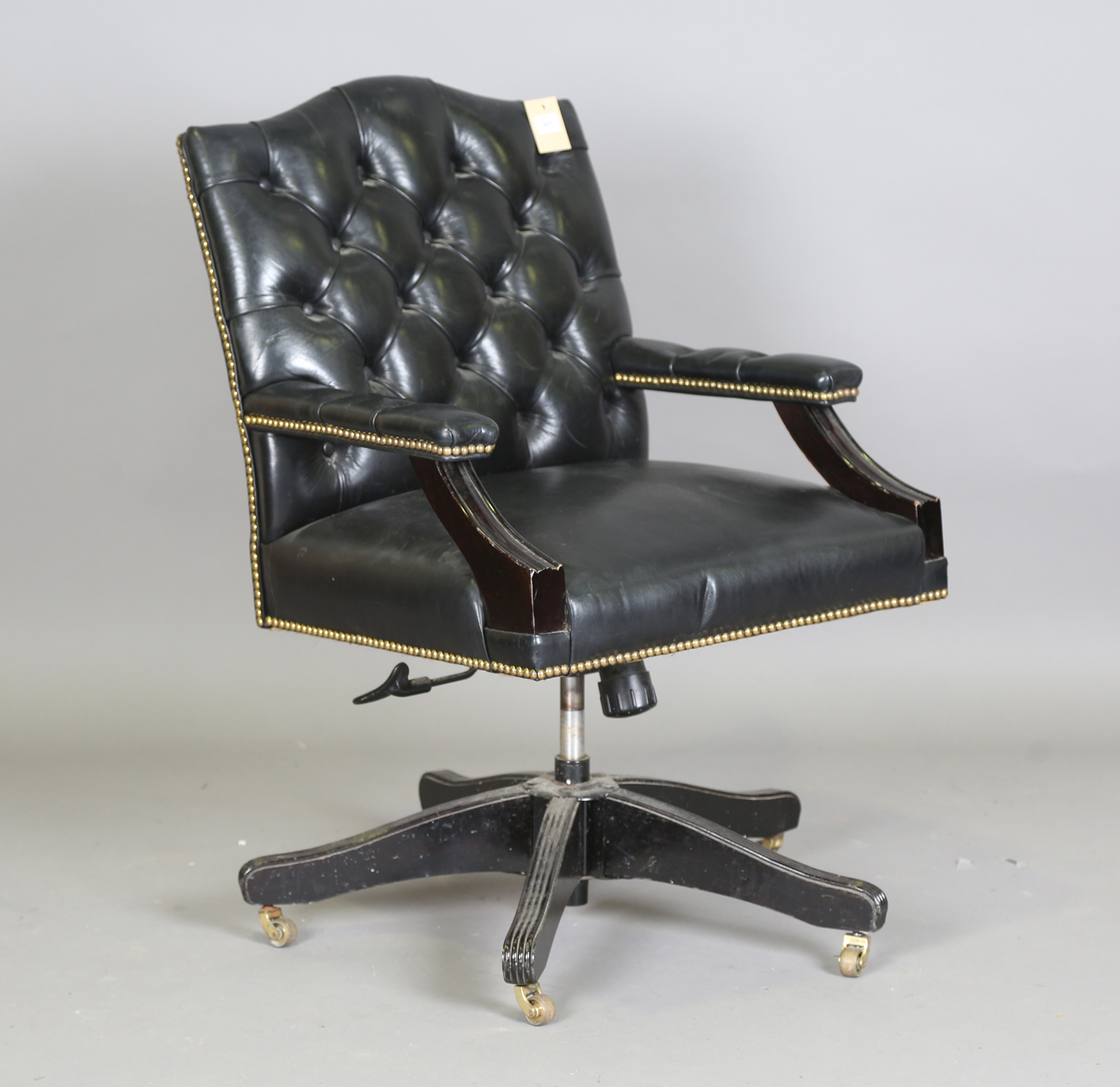 A late 20th century revolving desk chair, upholstered in buttoned black leather, height 95cm,