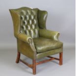 A 20th century George III style wing back armchair, upholstered in buttoned green leather, on