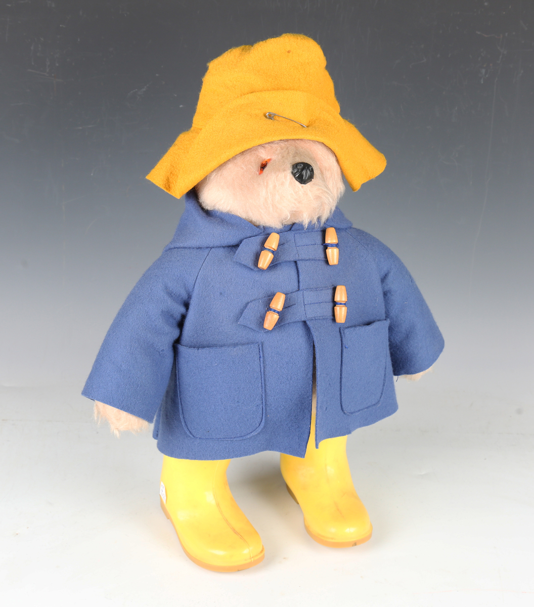 A Gabrielle Designs Ltd Paddington Bear wearing a yellow felt hat, duffle coat and yellow Dunlop
