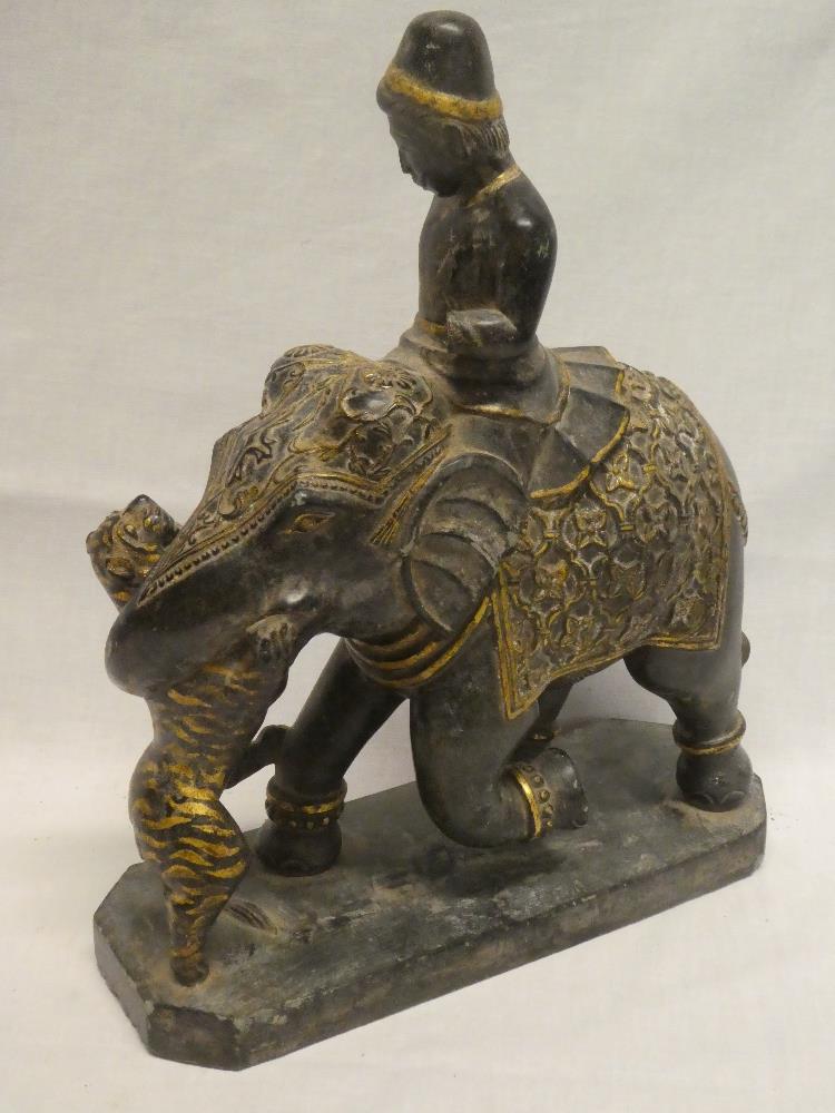 An unusual Eastern carved slate and gilt painted figure of a male riding an elephant,