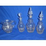 A good quality cut glass circular water jug with loop handle and three cut glass decanters and