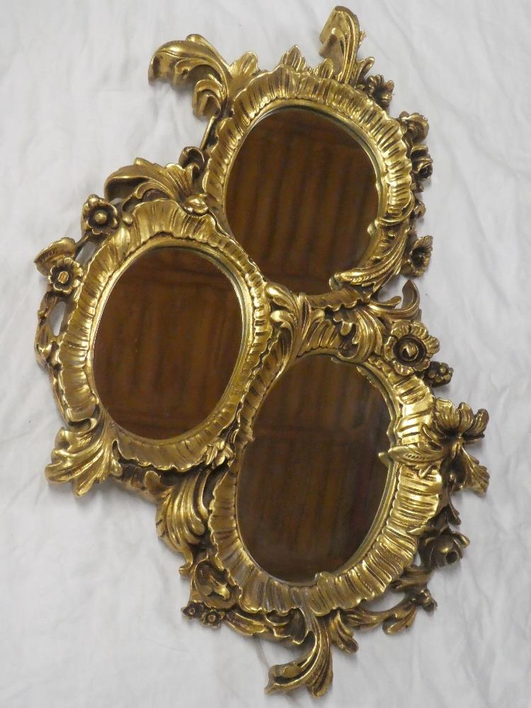 A modern three section oval wall mirror in floral and scroll mounts 36" long