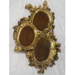 A modern three section oval wall mirror in floral and scroll mounts 36" long