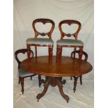 A Victorian mahogany oval dining table with turned column on scroll legs with a set of six mahogany