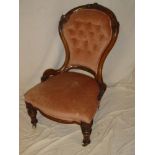 A Victorian carved walnut easy chair upholstered in pink buttoned fabric on turned legs with