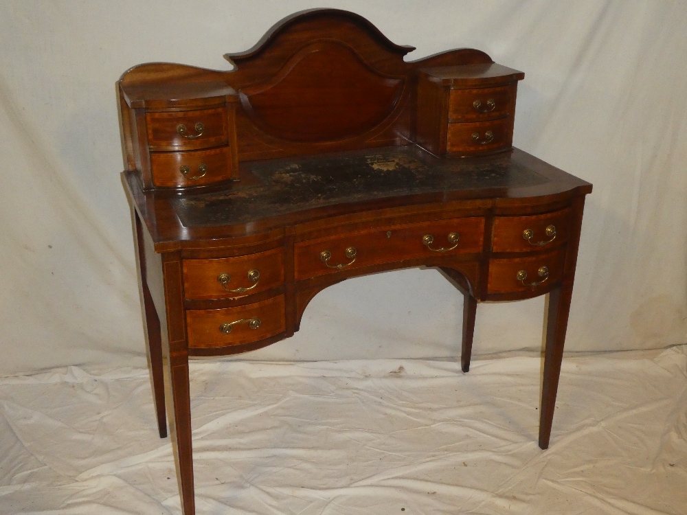 A late Victorian inlaid mahogany ladies writing desk with a single curved frieze drawer flanked by