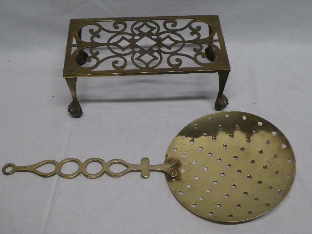 A 19th century brass milk skimmer with ornate handle and a brass rectangular kettle stand (2)