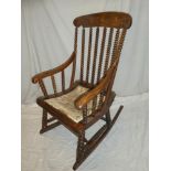A 19th century elm traditional rocking chair with bobbin turned back and upholstered seat
