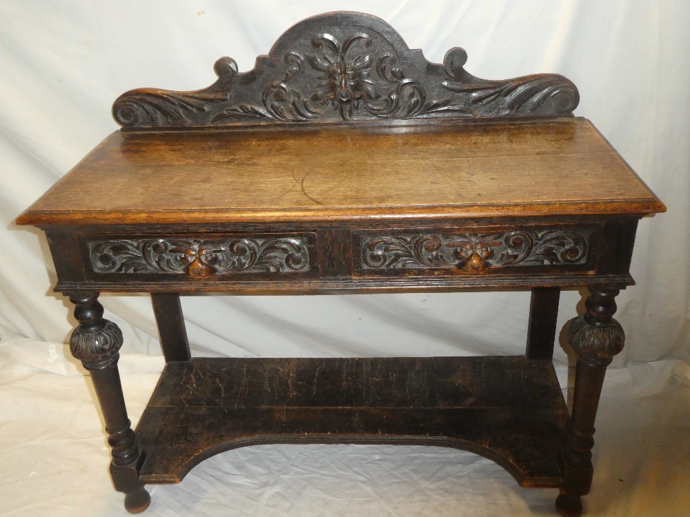 A late Victorian carved oak rectangular side table with two drawers in the frieze on turned