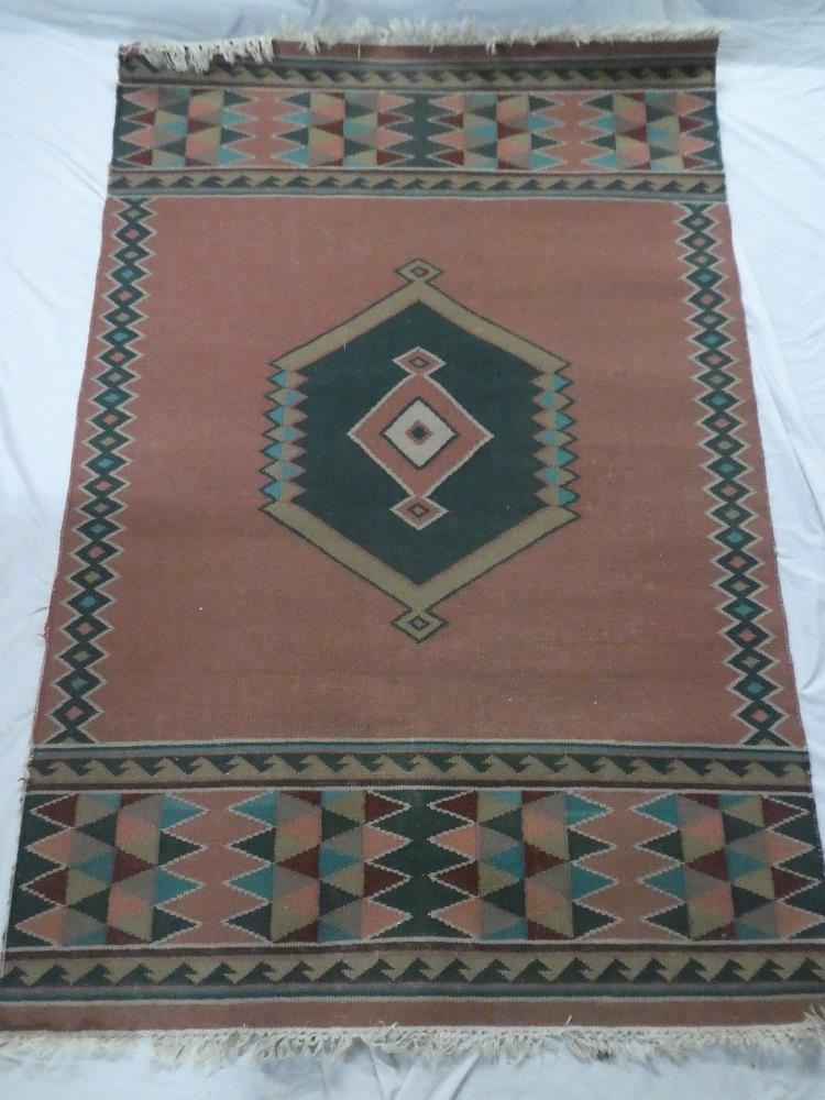 An Eastern-style flat weave wool rug with geometric decoration on red ground 72" x 48"