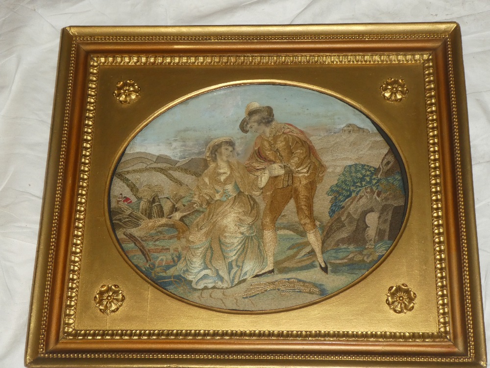 A George III embroidered silk-work oval panel depicting a male and female in a country clearing 12"