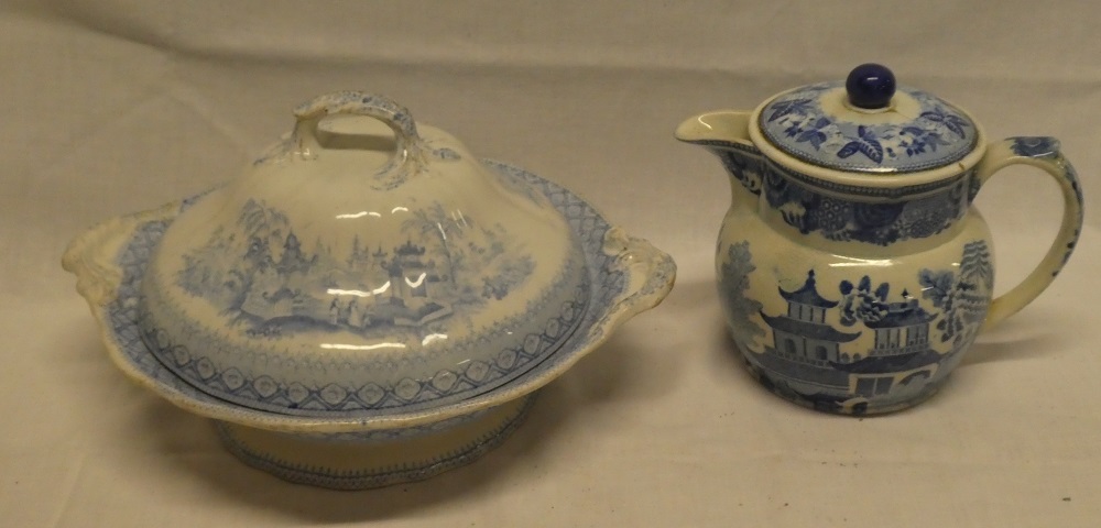 An early 19th Century pottery tapered jug and cover with blue and white landscape decoration (lid