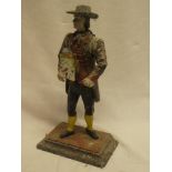 An old painted aluminium mantel clock in the form of a gentleman wearing a wide brimmed hat,