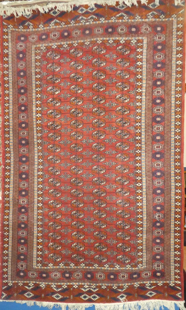 An old Eastern hand-knotted Bokhara wool rug with medallion decoration on red ground 98" x 60"