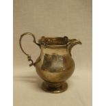 A George V silver baluster shaped cream jug with scroll handle,