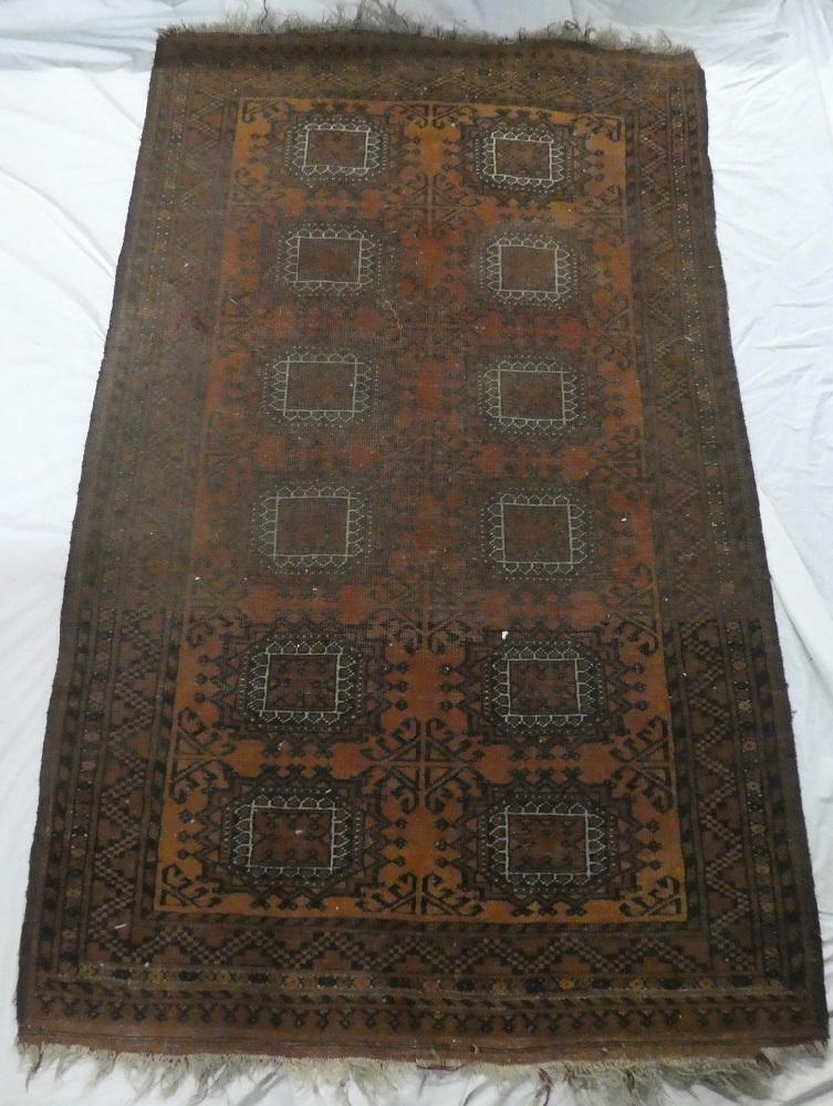 An old Eastern hand-knotted wool rug with geometric decoration on brown ground,