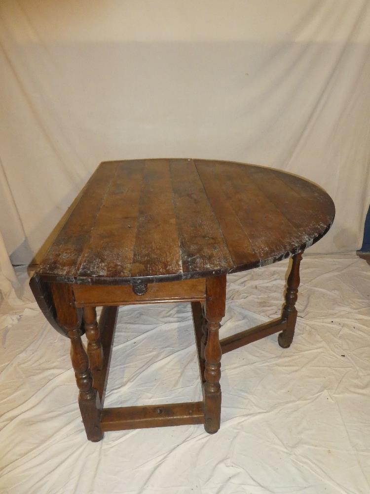 A Charles II and later oak oval gate leg dining table with a drawer in each end on baluster tapered