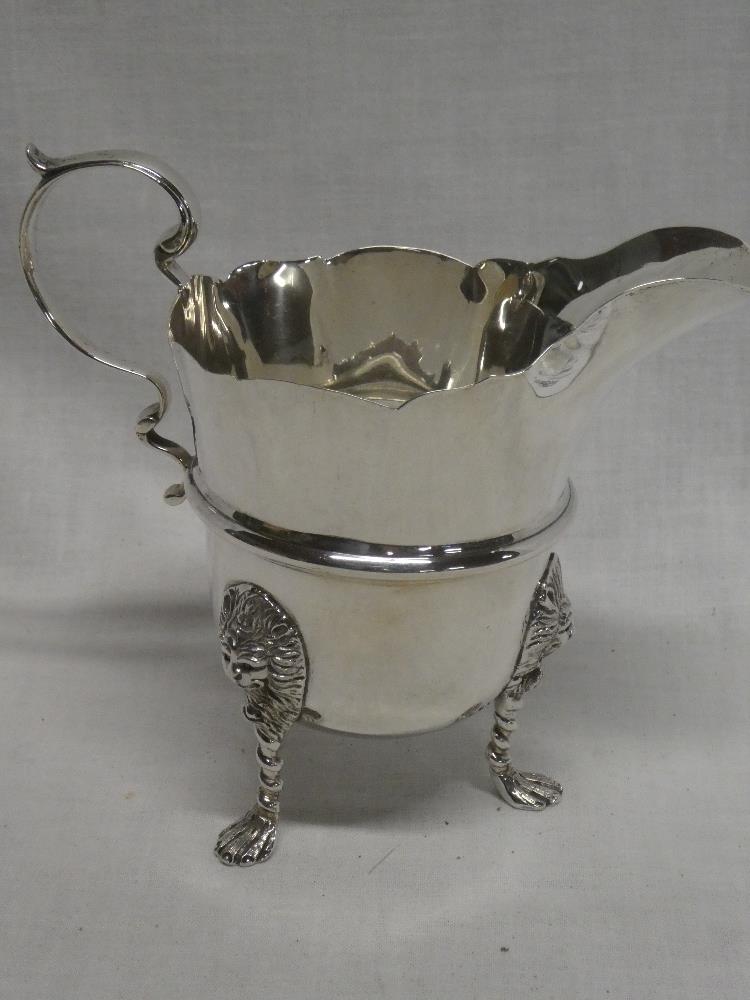A George V Irish silver classical-shaped cream jug with scroll handle and Lions mask feet,
