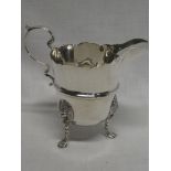 A George V Irish silver classical-shaped cream jug with scroll handle and Lions mask feet,