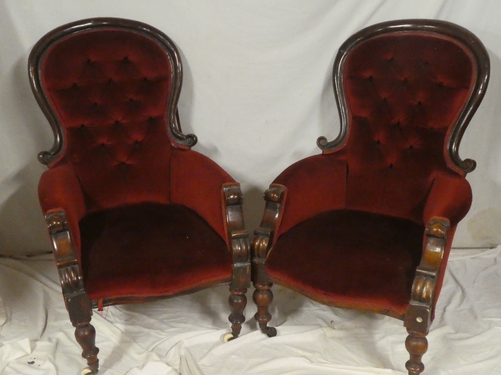 A pair of Victorian mahogany ladies and gents easy chairs upholstered in red buttoned fabric on