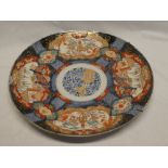 A 19th Century Japanese pottery circular charger with panels of flowers and emblems,