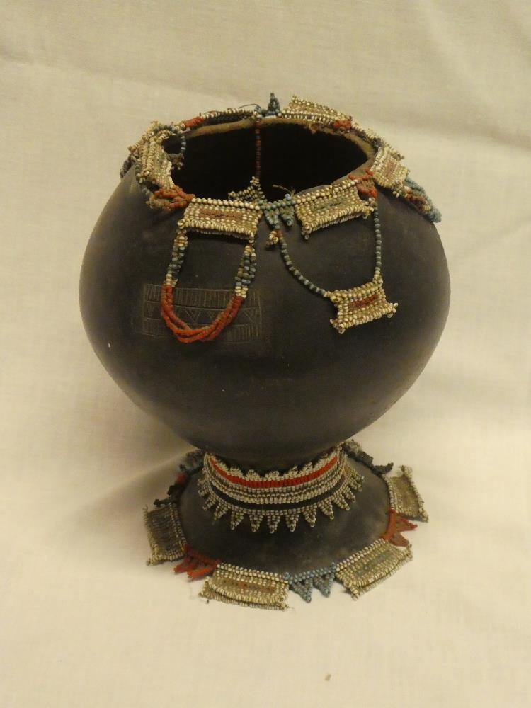 An unusual African terracotta pedestal bowl decorated with various beadwork panels and decoration