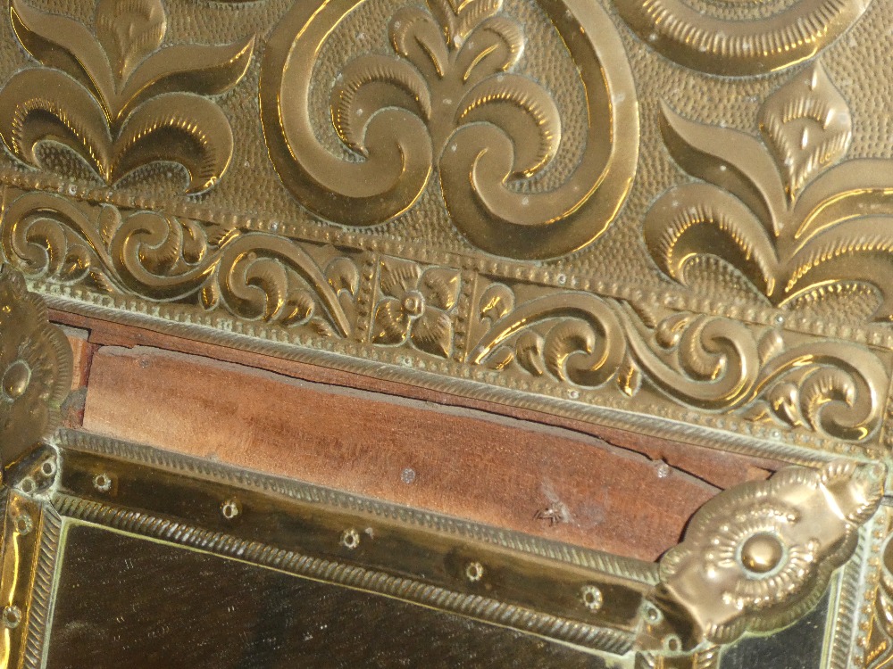 An unusual brass embossed rectangular cushion-framed mirror with raised scroll decoration 26" long - Image 2 of 2