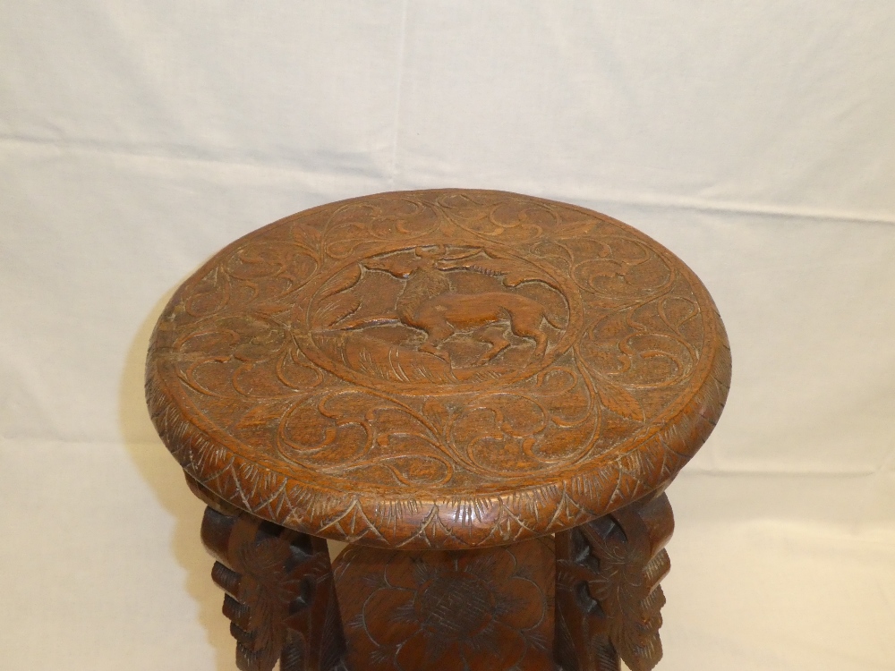 A Burmese carved teak circular two-tier occasional table with animal decorated top on scroll-shaped - Image 2 of 2