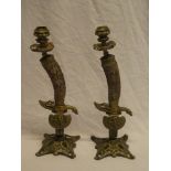 A pair of unusual brass mounted candlesticks in the form of hunting sword hilts with raised dog and