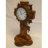 An unusual mantel clock with circular enamelled dial in carved oak crucifix-style case