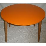 A 1960s circular dining table with orange formica top and detachable legs,