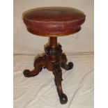 A Victorian carved mahogany circular revolving piano stool with leather upholstered seat on carved